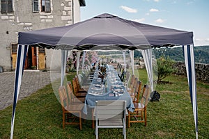 Tent set up in a grassy area outdoors, ready for hosting a formal dinner event