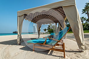 Tent with sun beds on a sandy beach overlooking the Burj Al Arab Hotel
