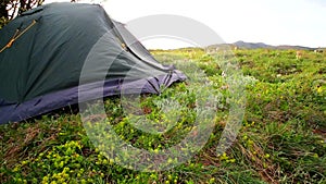 Tent sways in strong wind at beautiful morning mountain landscape