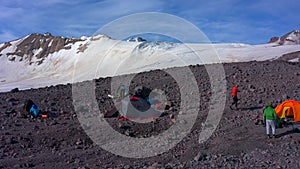 Tents camp in front of Mount Elbrus. Travelers collect their backpacks.