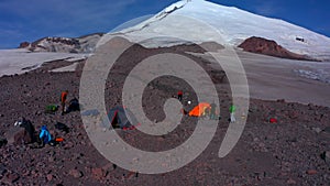 Tents camp in front of Mount Elbrus. Travelers collect their backpacks.