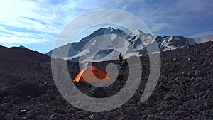 Tents camp in front of Mount Elbrus. Travelers collect their backpacks.