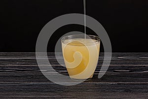 Tepache - Popular mexican fermented pineapple drink.  Chilled drink poured into glass. Dark background, copy space