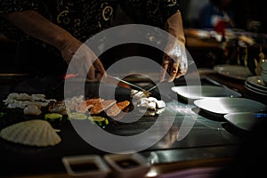 teppan show at a traditional Japanese restaurant. hands of the cook. Japanese cook prepares meat, fish, rice, vegetables