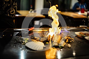 teppan show at a traditional Japanese restaurant. hands of the cook. Japanese cook prepares meat, fish, rice, vegetables