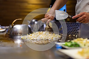 Teppanyaki chef preparing food on metal plate