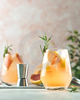 Tequila cocktail or cold lemonade with grapefruit juice, tinted with the aroma of a fresh sprig of rosemary