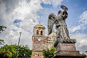 TEQUILA, JALISCO, MEXICO - JULY - 2015: Angel in the foreground with the village church behin
