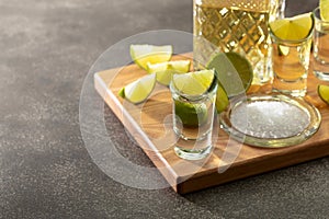 Tequila with sea salt and lime slices on a cutting board