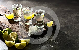 Tequila with sea salt and lime slices on a old cutting board