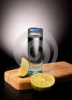 Tequila shot with lemon on black background