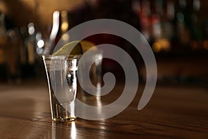 Tequila shot with lime on counter in bar, space for text. Alcoholic cocktail