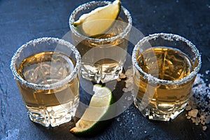 Tequila shot with lime and sea salt on black table