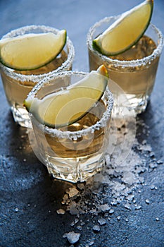 Tequila shot with lime and sea salt on black table