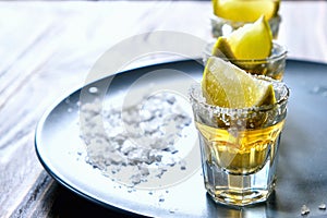 Tequila shot with lime and sea salt on grey plate