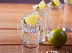 Tequila shot with lime and sea salt onwooden table
