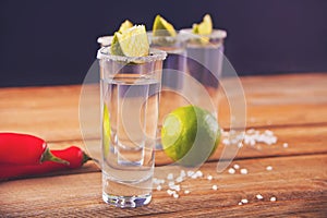 Tequila shot with lime and sea salt on the wooden table
