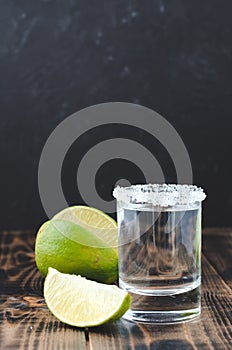 Tequila shot and lime slice on wooden table/Tequila shot and lime slice on wooden table with copy copyspace dark background