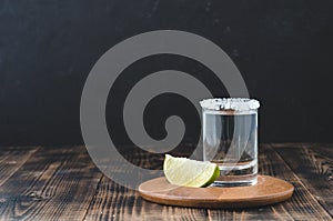 Tequila shot and lime slice on wooden table/Tequila shot and lime slice on wooden table with copy copyspace on dark background