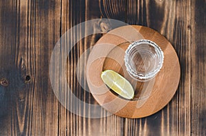 Tequila shot and lime slice on wooden table/Tequila shot and lime slice on wooden table with copy copyspace. Top view