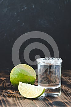 Tequila shot and lime slice on wooden table/Tequila shot and lime slice on wooden table. Dark background