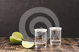 Tequila shot with lime slices and salt on wooden table/Tequila shots and lime slice on wooden table.With copy space on black