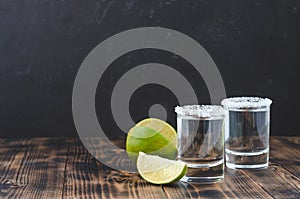 Tequila shot with lime slices and salt on wooden table/Tequila shots and lime slice on wooden table.With copy space on black