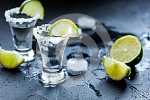 Tequila shot with salt and ice on dark background