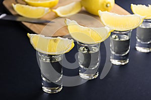 Tequila shots with lemon slices and pieces in the background.