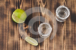 Tequila shots with lime slices and salt on wooden table/Tequila shots and lime slice on wooden table. Top view