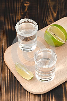 Tequila shots with lime slices and salt on wooden table/Tequila shots and lime slice on wooden table. Top view