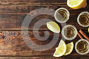 Tequila shots with salt, lime slices and cinnamon on wood table