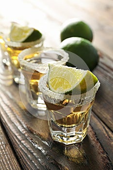 Tequila shots with salt and lime slices on wood table