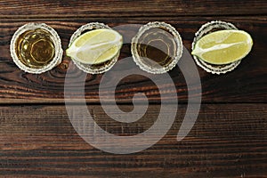 Tequila shots with salt and lime slices on wood table