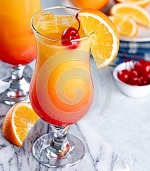 Tequila sunrise cocktail with cherry and orange slice