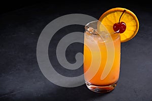 Tequila sunrise cocktail on dark stone background. With copy space.