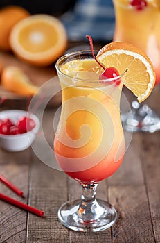 Tequila sunrise cocktail garnished with cherry and orange slice