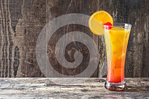 Tequila sunrise cocktail in glass on wood