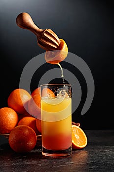 Tequila sunrise cocktail with ice and grenadine on a black background