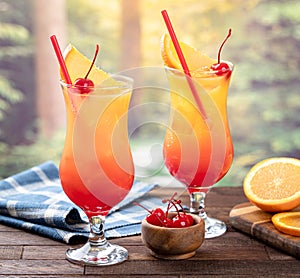 Tequila sunrise cocktail with orange slice and cherry