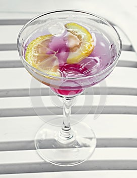 Tequila sunrise cocktail in a transparent glass with ice and slices of lemon, liquor