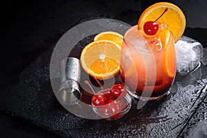 Tequila Sunrise cocktail on a wet black slate tray. Cocktail preparation set on a stone table with spaces for your text.