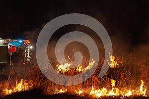 Teralba, NSW/Australia - October 24, 2012: Fire truck and firemen or firefighters backburning and extinguishing a wildfire grass