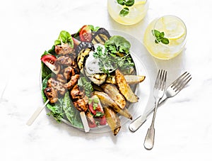 Teriyaki chicken skewers, roasted potatoes, vegetables, grilled eggplant and lemon mint cocktail - delicious appetizer plate,