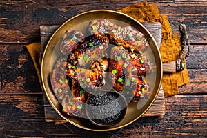 Teriyaki chicken wings with black sesame in a plate. Wooden background. Top view