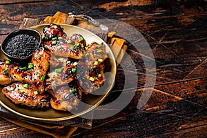 Teriyaki chicken wings with black sesame in a plate. Wooden background. Top view. Copy space