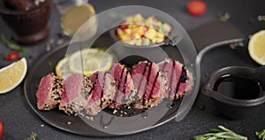 Teriyaki or soy sauce pours on sliced grilled fried tuna steak covered with sesame seeds and traditional mango salsa