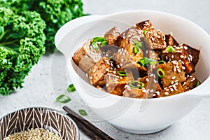 Teriyaki tofu with sesame seeds and green onion in white bowl. Vegan food concept