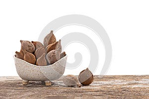 Terminalia bellirica or Beleric Myrobalan fruits in bowl on the wooden table with clipping path