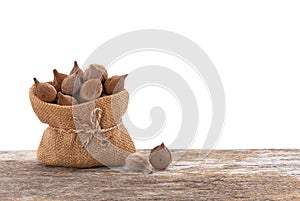 Terminalia bellirica or Beleric Myrobalan fruits in sack on the wooden table with clipping path